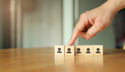 close up businessman manager hand point on cube wood with candidate man icon for choosing  and select new employee to company for we are hiring and team building concept