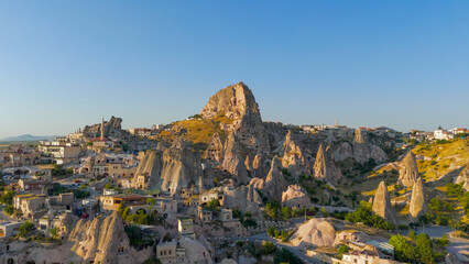 Obraz premium Uchisar, Nevsehir, Turkey - July 13, 2025: Aerial view blending ancient Uchisar Castle with modern Uchisar town and tourist facilities.. Aerial View