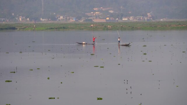 Shot of a fisherman catching fish using country boats with tiny birds flying around at Deepor Beel Guwahati Assam Long Shot