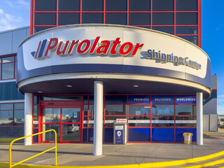 Naklejka premium Calgary, Alberta, Canada. Jan 19, 2026. Exterior of a Purolator Shipping Centre building with blue and red corporate branding and glass windows.