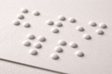 Close-up of embossed Braille text on white paper texture for accessibility and blindness concept