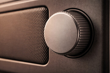 Close-up of textured volume control knob and speaker grille on electronic audio equipment with warm lighting
