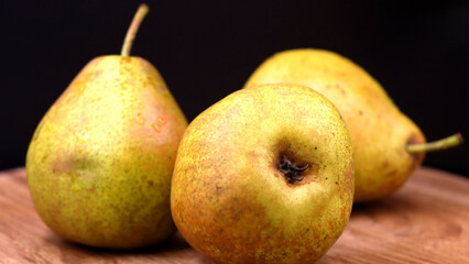 Realistic fresh pears on wood with dark background.