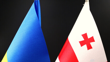 Ukrainian and georgian flags together on dark background.