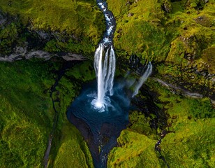 Aerial view of a cascading waterfall flowing through a lush, green landscape