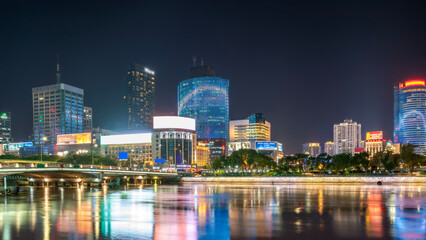 Obraz premium Night View of Modern City with Illuminated Skyscrapers