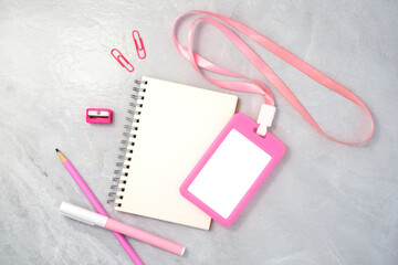 Pink plastic badge with book and stationery on white stone texture background. Template designed for employees of company