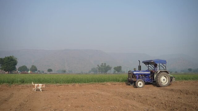 indian farmer working with tractor at agriculture field 