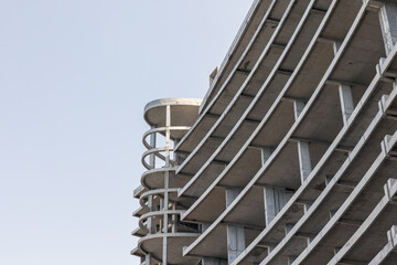 Naklejka premium A concrete building under construction rises with circular ramp columns