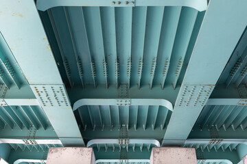 Obraz premium Perspective view of the underside of a teal-painted steel bridge
