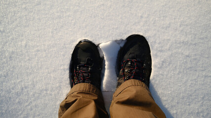 Person standing on snow wearing winter boots, top view
