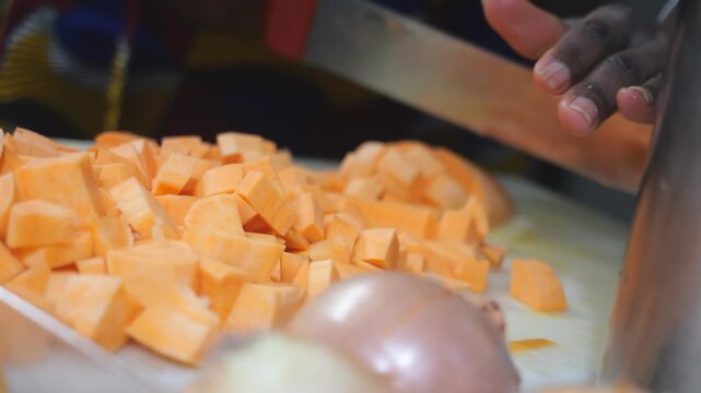 Close up of an African chef hands cutting yam into concass&eacute; pieces, using Dioscorea rotundata known as yam, igname, &ntilde;ame, inhame and Ipomoea batatas called sweet potato, batata, slow motion