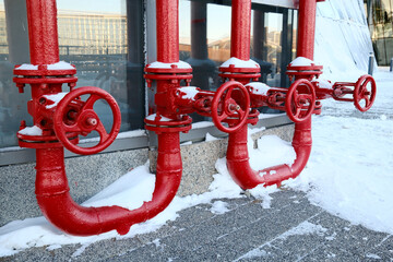 Red industrial gas pipes with valves covered in snow outdoors