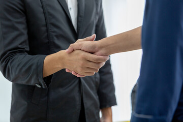 Close-up of professional business handshake between two people in formal attire, symbolizing agreement, trust, partnership in corporate setting. Perfect for business deal and collaboration concepts.