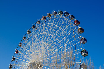 Ferris wheel structure against blue sky, amusement park attraction