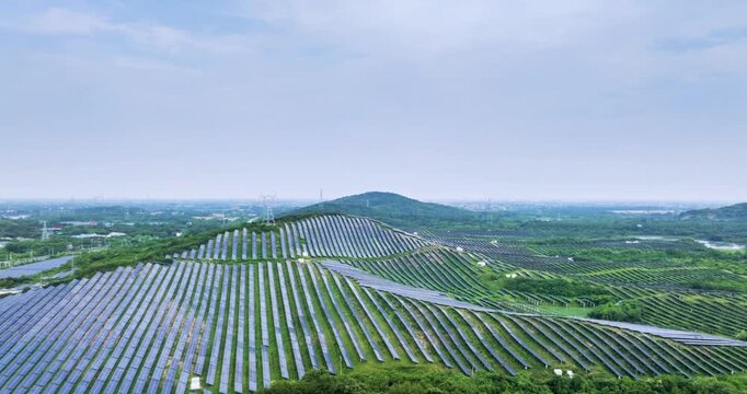 Aerial time-lapse of a hillside solar farm nestled in lush green mountains, renewable energy harmonizing with nature