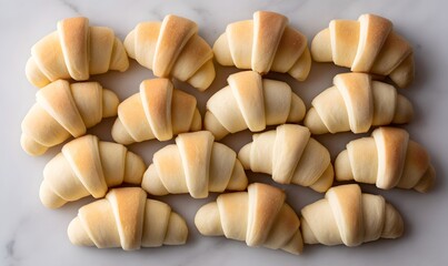 neatly arranged and lined up small crescent rolls, each rolled in white dough with the corners folded back to form an opening at one end