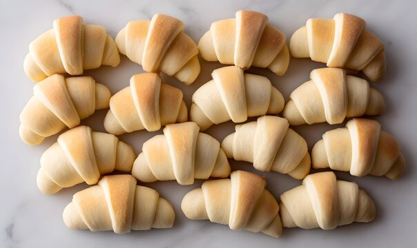 neatly arranged and lined up small crescent rolls, each rolled in white dough with the corners folded back to form an opening at one end