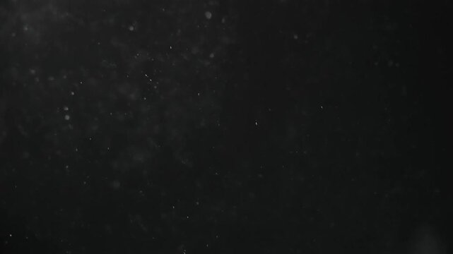 Fine Ash Particles Drifting Down in Slow Motion on Dark Background