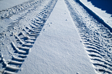 Snow surface with clear tire tracks and strong sunlight shadows