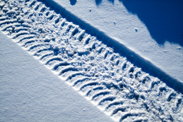 Snow surface with clear tire tracks and strong sunlight shadows