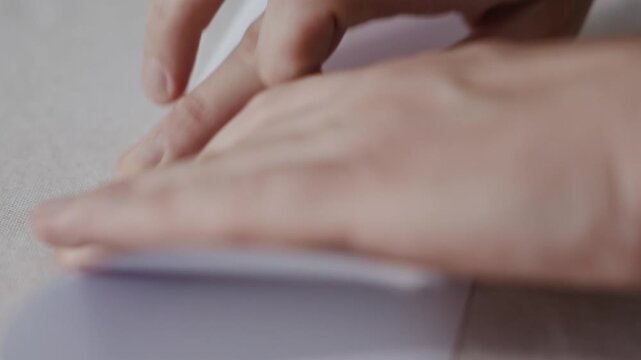 Extreme close-up from above showing an adult man smoothing a paper fold with fingertips while assembling a paper airplane. Camera emphasizes texture, crease line and controlled motion. High quality 4k