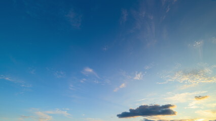 Wide blue sky at sunset, scattered clouds tinged with pink and gold, soft gradient from azure to indigo, peaceful horizon, cinematic atmospheric texture suggesting gentle motion