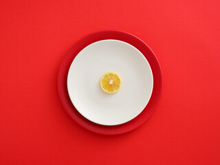 Lemon slice on white plate with red background