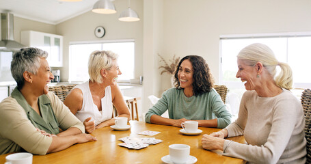 Fototapeta premium Cards, friends and senior woman at table for chat, weekend reunion and funny conservation for entertainment. Tea party, laugh and elderly people with smile in home, gossip and bonding for connection