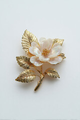 Gold flower brooch mother of pearl petal jewelry accessory vintage style, ornate gold leaf pin on white background, elegant bridal detail, luxury gift concept, closeup studio shot