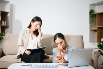 Stressed Asian businesswomen working together at home office. Financial problem, work stress, burnout, teamwork, budget planning