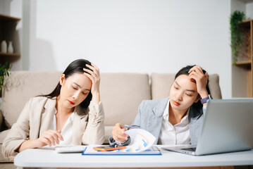 Stressed Asian businesswomen working together at home office. Financial problem, work stress, burnout, teamwork, budget planning