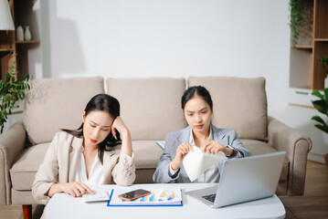 Stressed Asian businesswomen working together at home office. Financial problem, work stress, burnout, teamwork, budget planning
