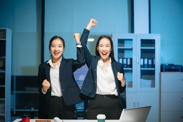 Confident Asian businesswomen smiling and showing thumbs up in modern office. Professional teamwork, success, trust, leadership