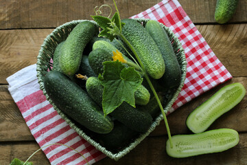Fresh cucumbers in heart shaped basket on wooden table