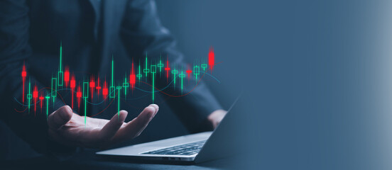 Businessman working on laptop with glowing candlestick stock chart floating above hand, financial analysis concept, online trading, investment management, forex market, fintech.