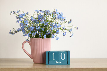 Forget-me-not flowers in pink mug with june 10 calendar