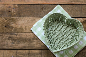 Heart shaped green wicker basket on rustic wooden table