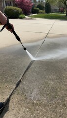 High Pressure Water Cleaning Concrete Driveway. Outdoor maintenance washing dirty stain on pavement to bright white. Housework chore removing black grime from street surface.