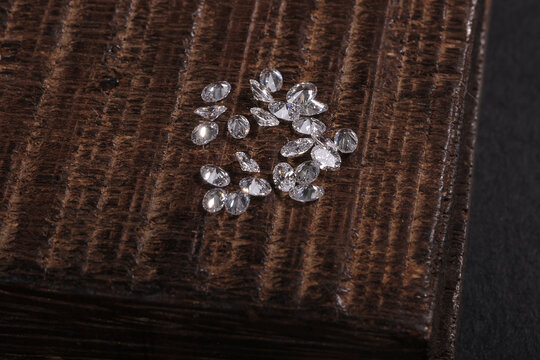Close-up of loose cut diamonds scattered on a textured wooden surface, showcasing brilliance, clarity, and luxury gemstone craftsmanship.