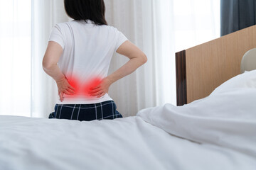 Women with lower back pain sitting by the bed