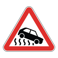a red triangular road sign warns of slippery road conditions and potential vehicle skidding