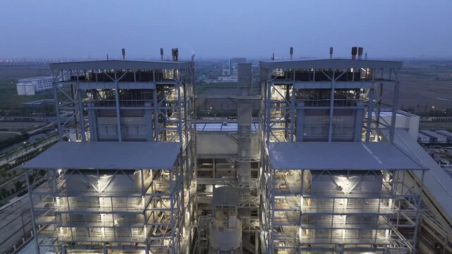 Industrial plant at night with illuminated steel-frame buildings and facility infrastructure