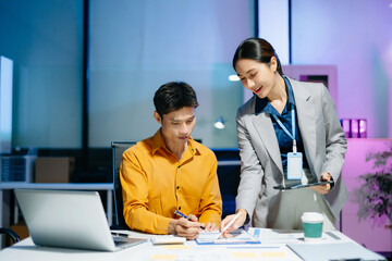 Obraz premium Asian business colleagues collaborating in modern office, using tablet and laptop for planning, consulting, teamwork and digital business strategy.