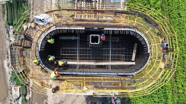 Aerial view of an elliptical underground structure under construction with exposed reinforcement and formwork