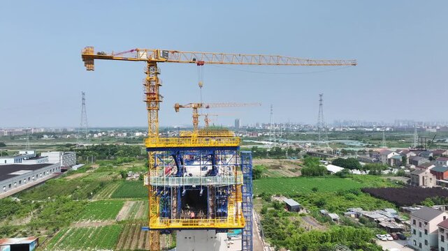 Yellow tower crane lifting components for high-rise building construction at a daytime construction site