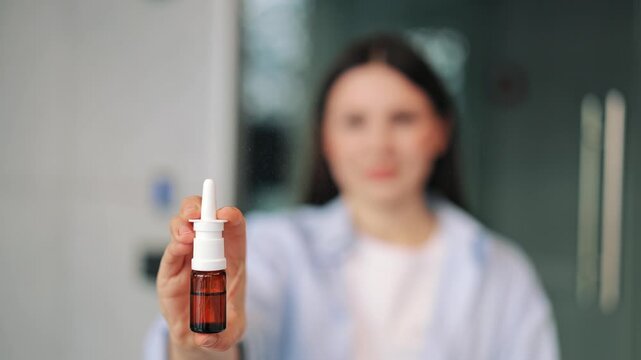 Woman confidently presents a nasal spray bottle, focusing attention on this medication. Product brings relief comfort for common cold symptoms or allergies, promoting well-being and health with trust.