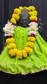 Mata Chhaya Devi, the divine consort of Shani Dev, depicted in a serene dark stone form and beautifully adorned with vibrant yellow marigold and white flower garlands