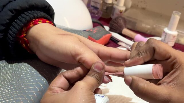 Close-up of a professional nail technician shaping nails during a manicure session, showcasing beauty care and grooming services.