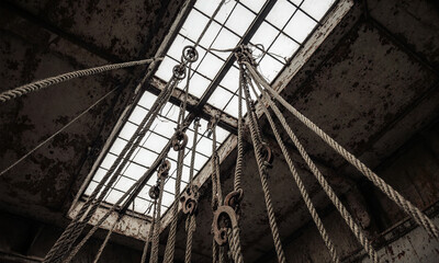 Ropes and Pulleys. A complex and tangled system of old ropes and rusted pulleys hangs motionless from the high ceiling